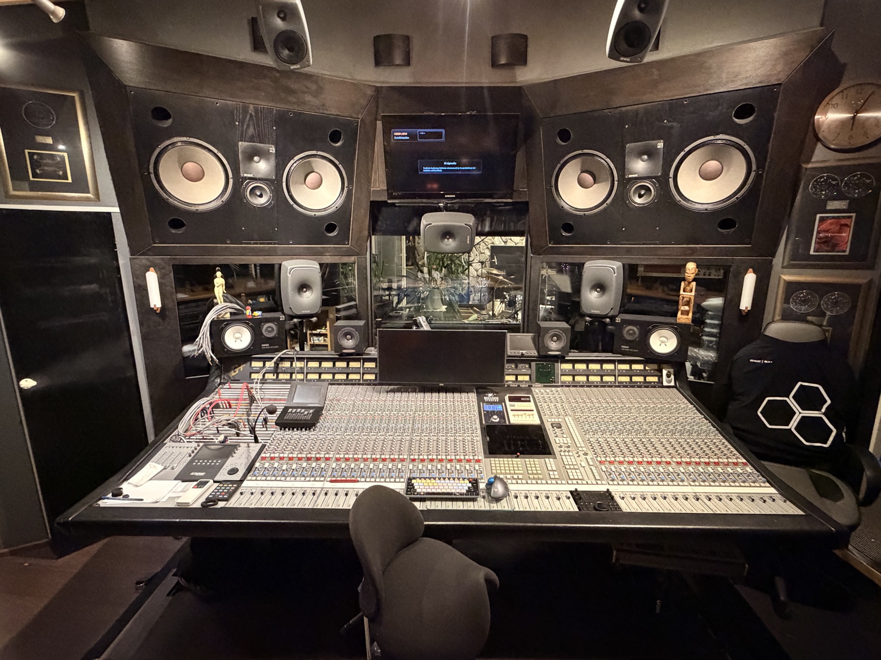 Main control room with large monitors and an analogue mixing console